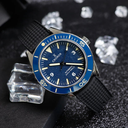 Montre de plongée automatique CRONOS pour homme avec cadran bleu, lunette unidirectionnelle et bracelet en caoutchouc noir, posée sur fond sombre avec des cubes en diamants
